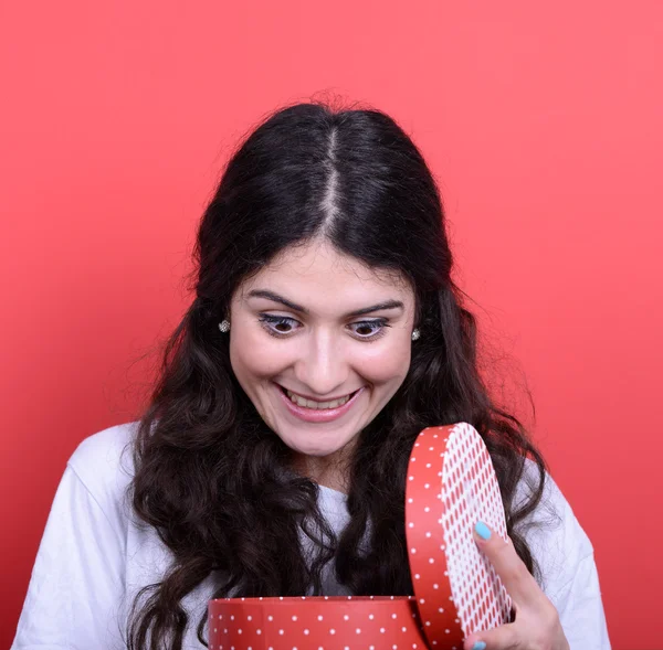 Portrait of happy woman opening gift box against red background — Stock Photo, Image