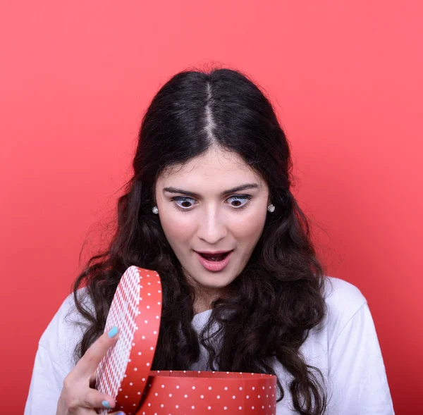 Portrait of happy woman opening gift box against red background — Stock Photo, Image