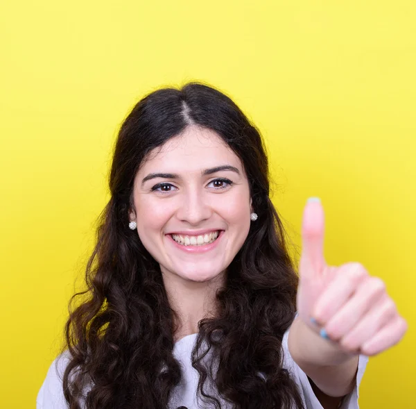 Portrait of happy woman with thumbs up against yellow background — Stock Photo, Image