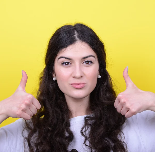 Portrait of happy woman with thumbs up against yellow background — Stock Photo, Image