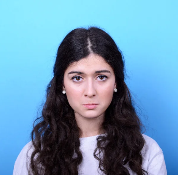 Portrait of sad girl against blue background — Stock Photo, Image