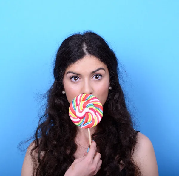 Portrait of woman licking lollipop against blue background — Stock Photo, Image