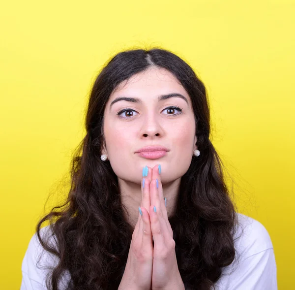 Portrait of woman praying against yellow background — Stock Photo, Image