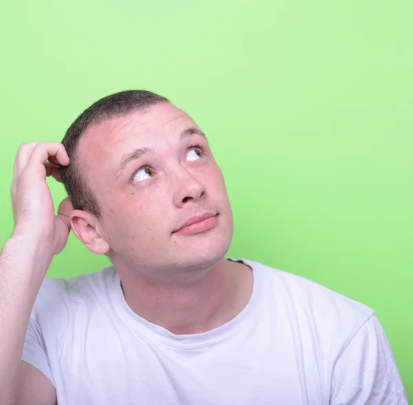 Портрет смущенного человека на зеленом фоне, смотрящего вверх — стоковое фото