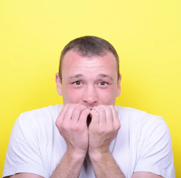 Портрет человека, грызущего ногти на жёлтом фоне — стоковое фото