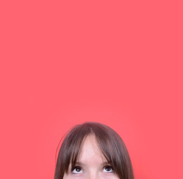 Portrait of beautiful girl looking up against red background — Stock Photo, Image