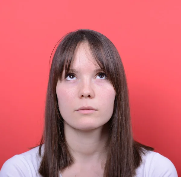 Portrait of beautiful girl looking up against red background — Stock Photo, Image