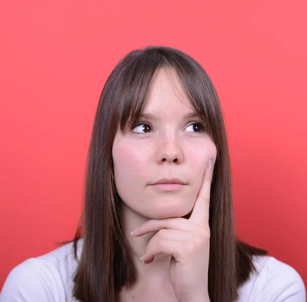 Portrait of beautiful girl thinking against red background — Stock Photo, Image