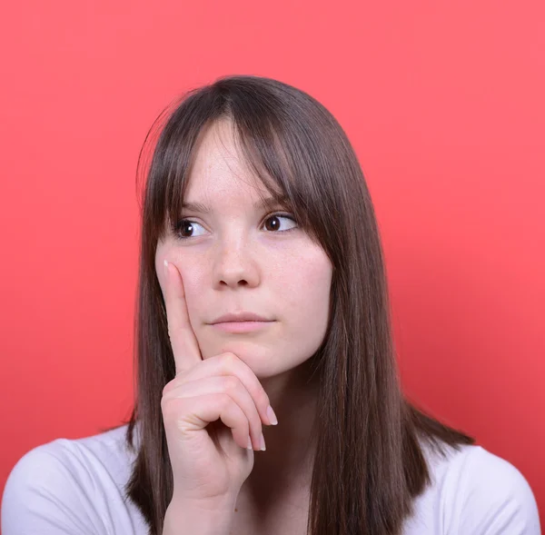 Portrait of beautiful girl thinking against red background — Stock Photo, Image