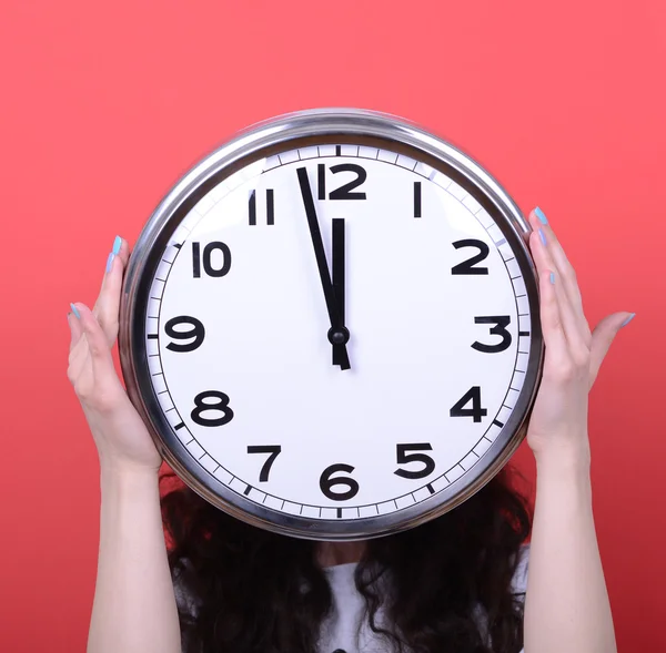 Portrait of girl holding huge office clock against red backgroun — Stock Photo, Image