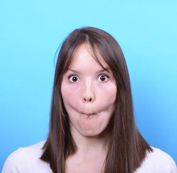 Портрет девушки со смешным лицом на синем фоне — стоковое фото