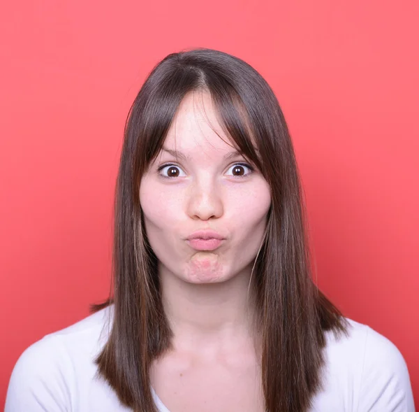 Porträt eines Mädchens mit lustigem Gesicht vor rotem Hintergrund — Stockfoto