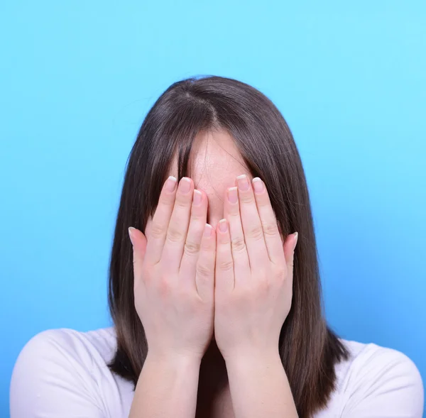 Portrait of covering her face with hands against blue background — Stock Photo, Image