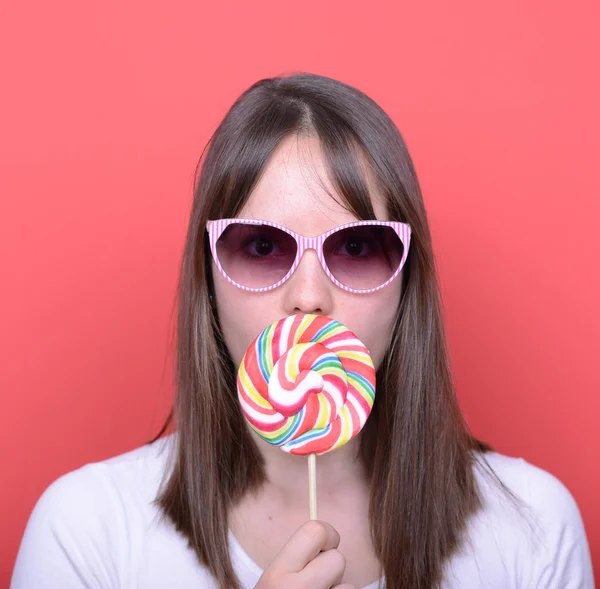 Portrait of woman with retro glasses and lollipop against red ba