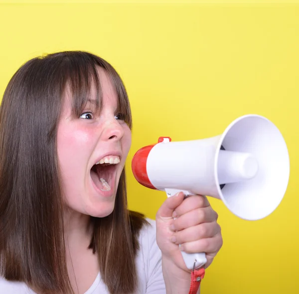 Retrato de una joven gritando con un megáfono contra el amarillo — Foto de Stock