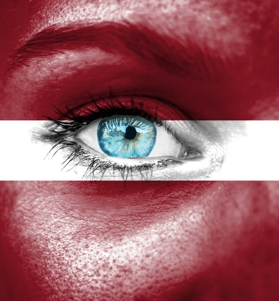 Лицо женщины, раскрашенное флагом Латвии — стоковое фото