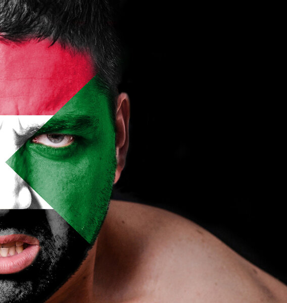 Портрет разгневанного человека с нарисованным флагом Судана
