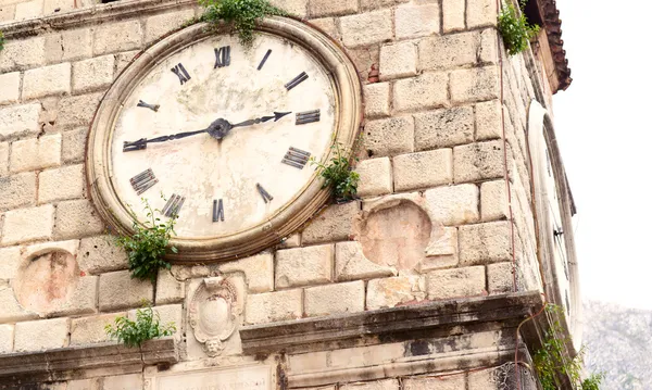 Old clock on a stone wall inside the town of Kotor — Stock Photo, Image