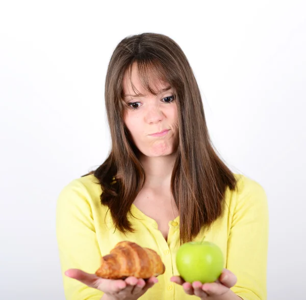 Mujer dudosa sosteniendo una manzana y croissant tratando de decidir w — Foto de Stock