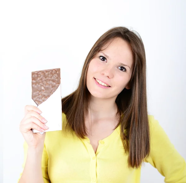 Jovem mulher comendo barra de chocolate contra fundo branco — Fotografia de Stock