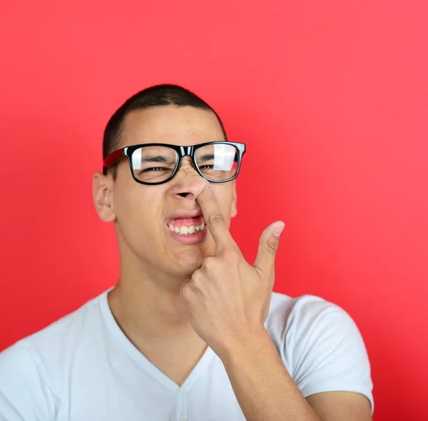 Portret van een grappige vent met vinger in zijn neus tegen rode rug — Stockfoto