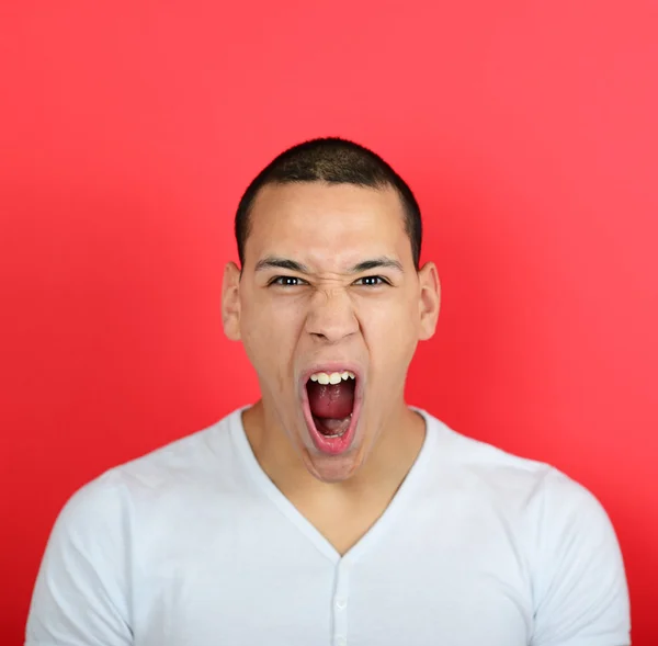 Портрет разгневанного человека, кричащего на красном фоне — стоковое фото
