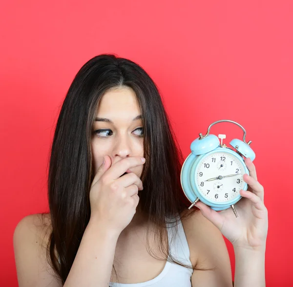 Retrato de menina no caos olhando assustado no relógio contra vermelho ba — Fotografia de Stock