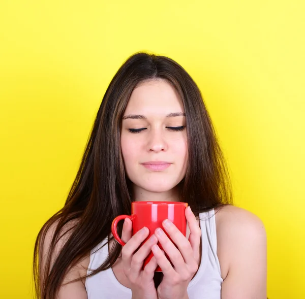 Retrato de mujer feliz disfrutando de taza de bebida caliente contra amarillo — Foto de Stock