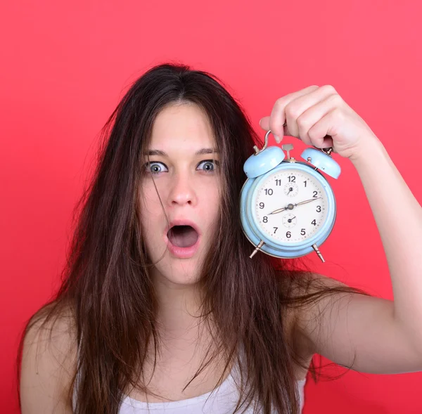 Porträt einer verschlafenen jungen Frau im Chaos, die die Uhr gegen sich hält — Stockfoto