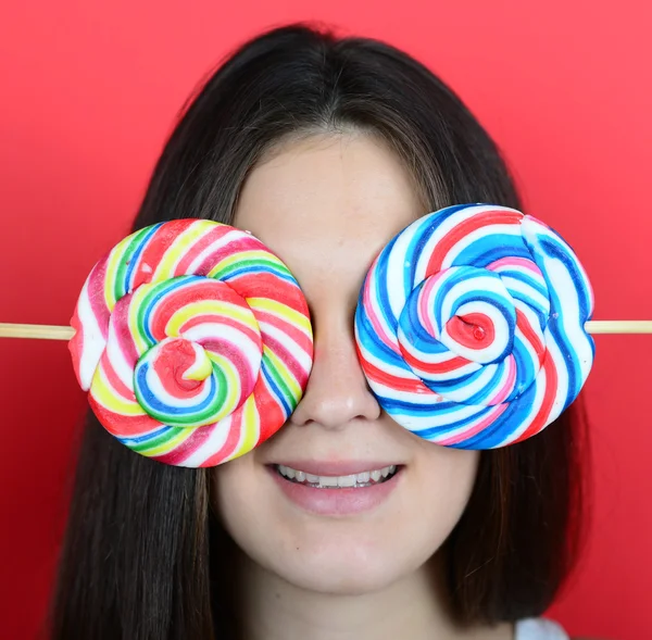 Portrait de femme couvrant les yeux avec des sucettes sur fond rouge — Photo