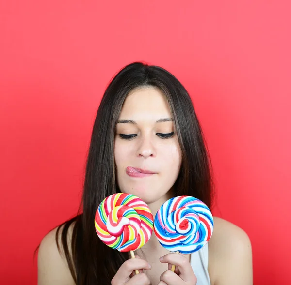 Portrait of woman holidng lollipops against red background — Stock Photo, Image