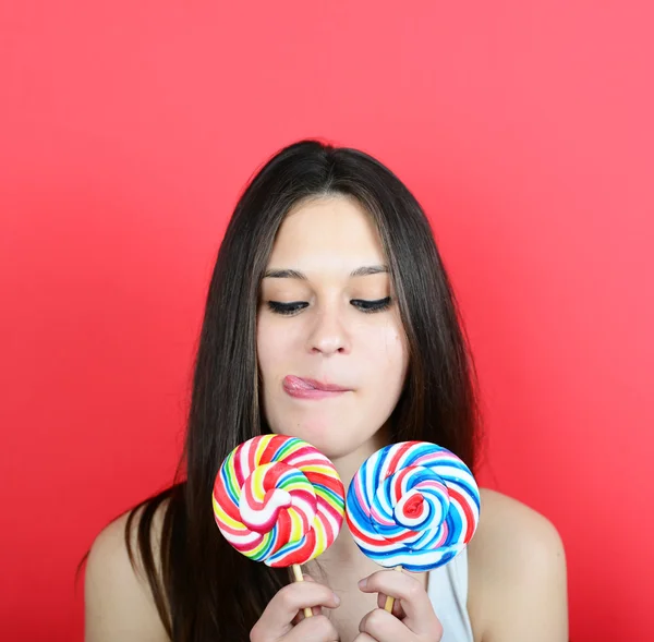 Retrato de mulher holidng pirulitos contra fundo vermelho — Fotografia de Stock