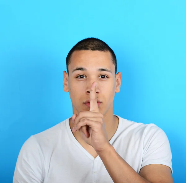 Portret van man met gebaar voor stilte tegen blauwe achtergrond — Stockfoto