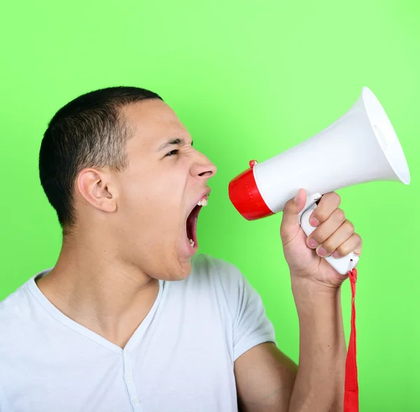 Portret van jonge man geschreeuw met een megafoon tegen groene ba — Stockfoto