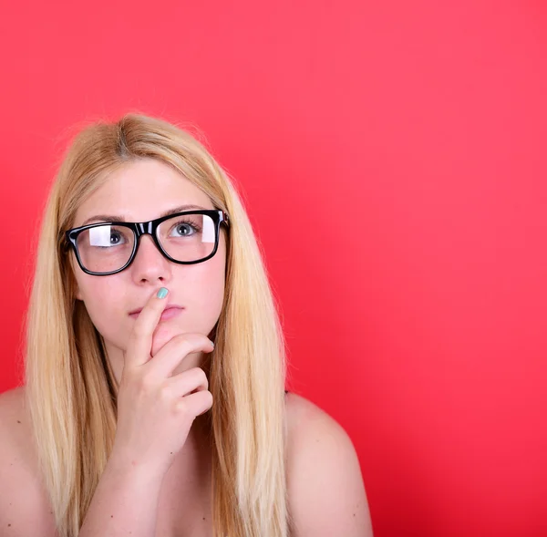 Portrait of beautiful girl looking up against red background — Stock Photo, Image