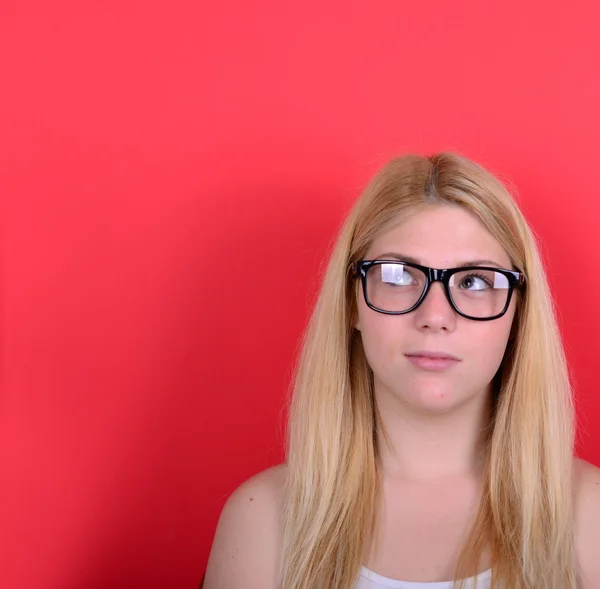 Portrait of beautiful girl thinking and looking up against red b — Stock Photo, Image