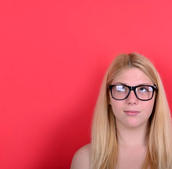 Portrait of beautiful girl thinking and looking up against red b — Stock Photo, Image