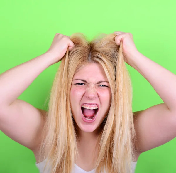 Portrait of desperate blond young woman pulling hair against gre — Stock Photo, Image