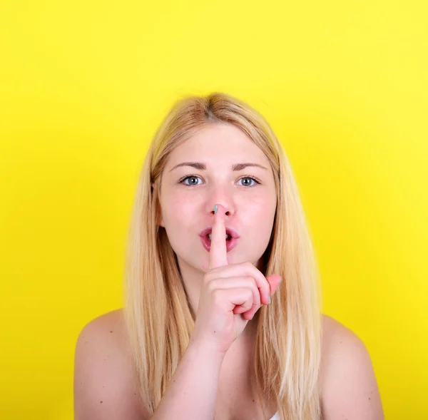 Portrait of girl with gesture for silence against yellow backgro — Stock Photo, Image