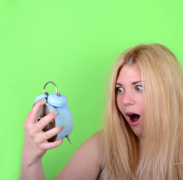 Portrait of sleepy young female in chaos holding clock against g — Stock Photo, Image