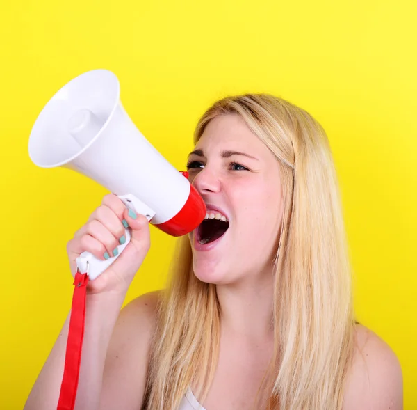 Retrato de mulher jovem gritando com um megafone contra amarelo — Fotografia de Stock
