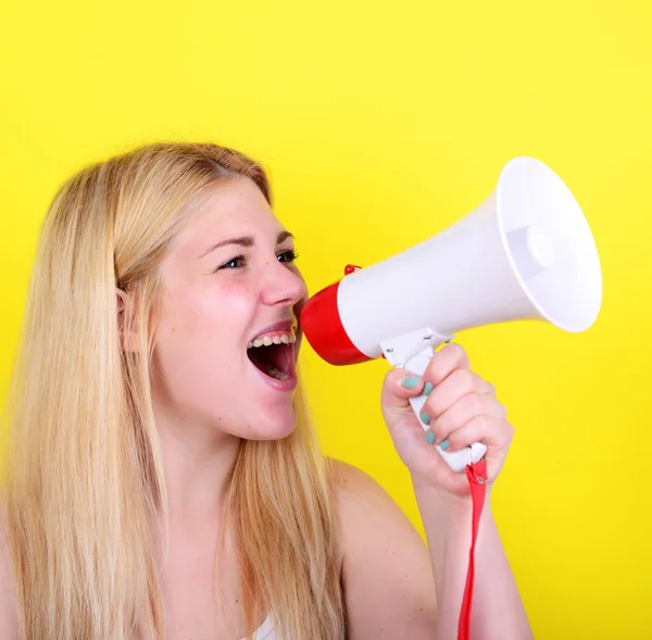 Retrato de una joven gritando con un megáfono contra el amarillo — Foto de Stock