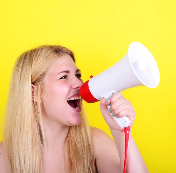 Portret van een jonge vrouw geschreeuw met een megafoon tegen geel — Stockfoto