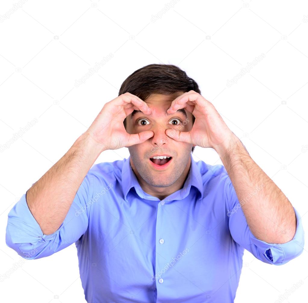 Portrait of young surprised man looking through his fingers like