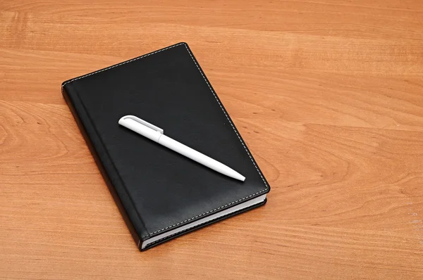 Black notepad and pen on table — Stock Photo, Image