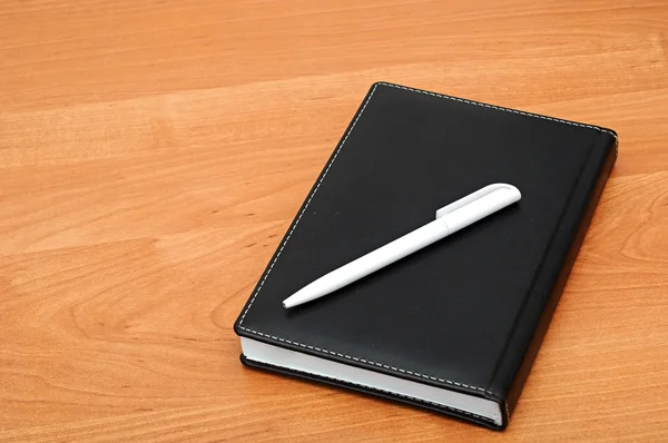 Notepad with pen on wood table — Stock Photo, Image