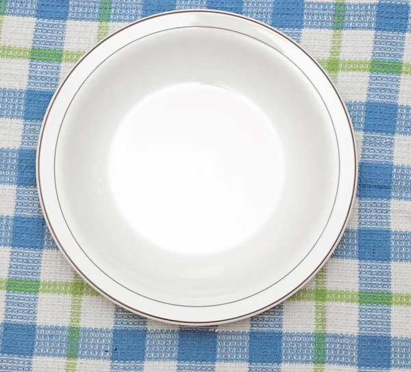 Άσπρο πιάτο στο μπλε ύφασμα ελεγμένο τραπεζομάντιλο — Φωτογραφία Αρχείου