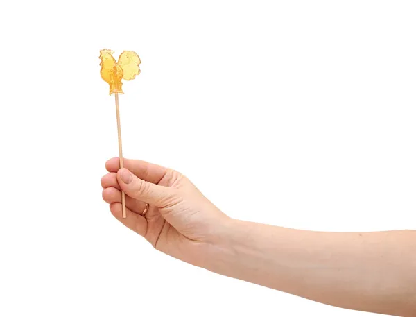 Sweet cockerel on stick in hand isolated on white — Stok fotoğraf