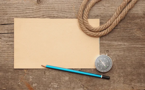 Brújula, papel viejo, lápiz y cuerda sobre fondo de madera — Foto de Stock