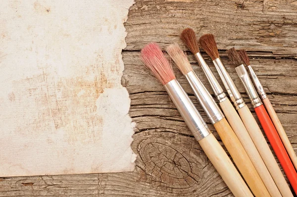 Pennelli per dipingere su vecchio sfondo in legno con carta bianca vintage — Foto Stock